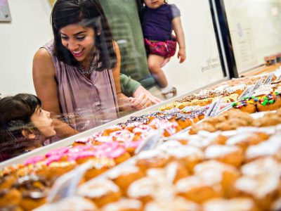 Mom and daughter browsing many delicious donuts in a downtown Alpharetta shop