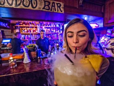 Woman sipping on a large smoking cocktail at the Voodoo Bar