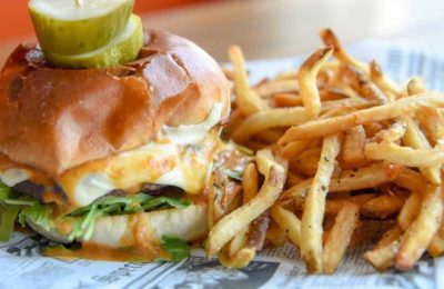 a cheeseburger and fries with pickle slices at Chiringa