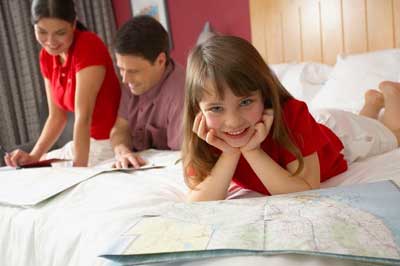 family planning a trip laying on hotel bed