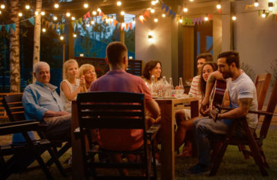 group of friends enjoying dinner and music outside on a porch