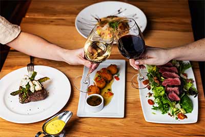 people clinking wine glasses over dinner