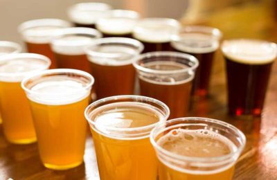 many plastic cups filled with various types of beer