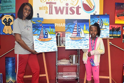 mom and daughter holding paintings