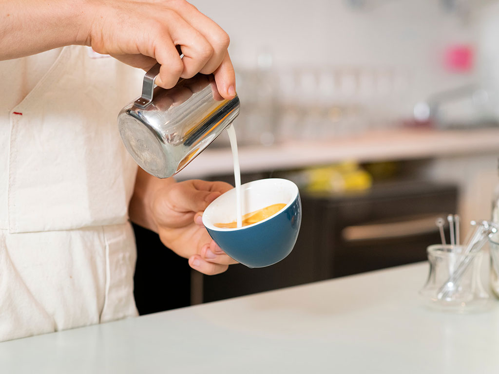 guy pouringsteamed milk into expresso