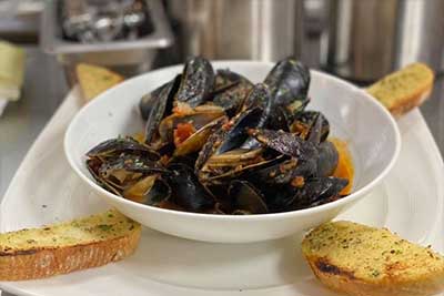 mussels in a bowl surrounded by garlic bread