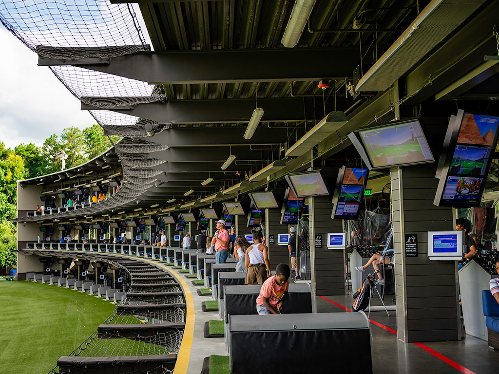 people hitting golf balls at topgolf