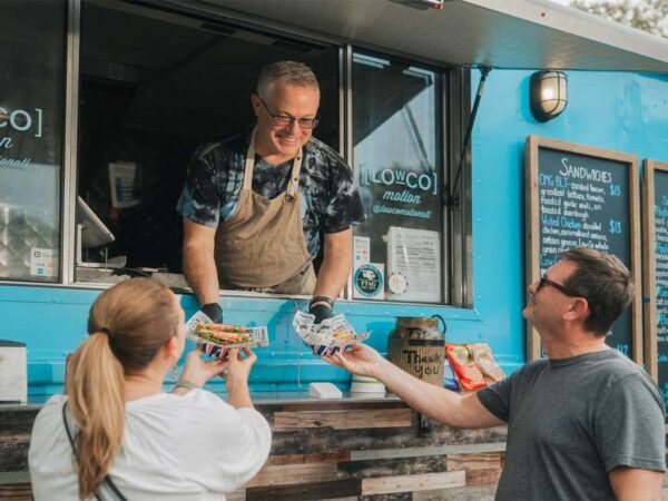 vendor handing food to people at food truck alley