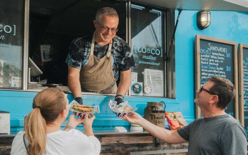 vendor handing food to people at food truck alley