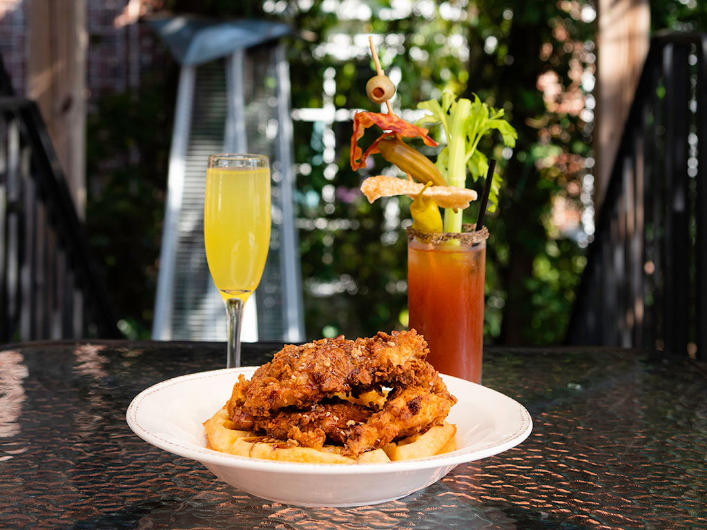 Oj, bloody mary and chicken and waffles on a table