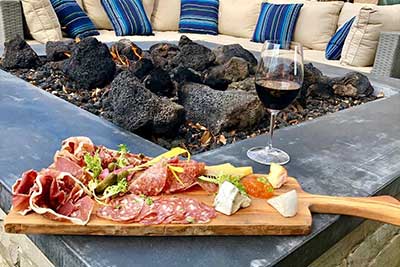 charcuterie board and glass of wine near fire