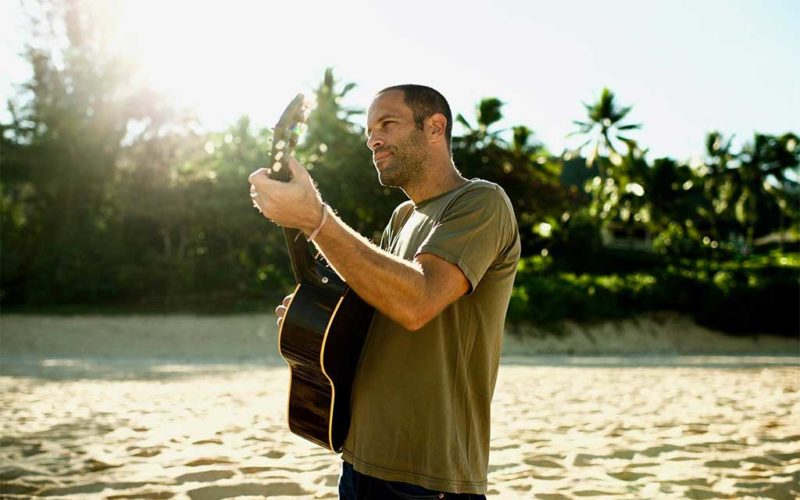 guiy with guitar on beach