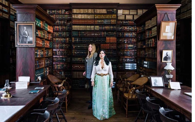 two woman standing in a library