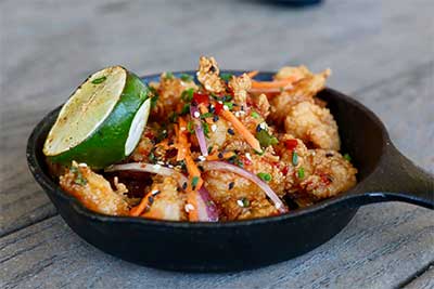 thai shrimp in a black skillet with lime on the side