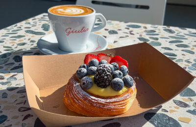 Coffee and pastry on outdoor cafe table.